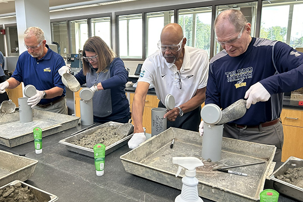 Engineering graduates creating time capusles with concrete in a lab