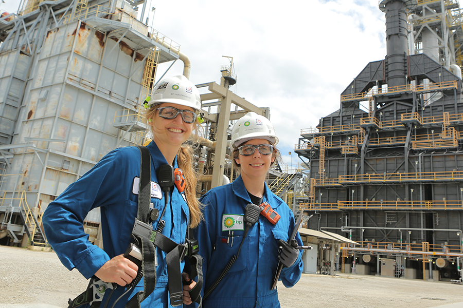 Two interns in hard hats and safety goggles standing outside at a Marathon/BP facility