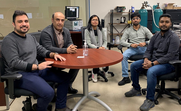 Dr. Abbas Semnani sitting around a table with members of the Adaptive Radiofrequency and Plasma Laboratory