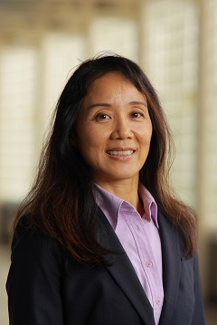 smiling dark haired woman in dark jacket and purple shirt