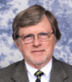 smiling man with glasses in brown suit and tie