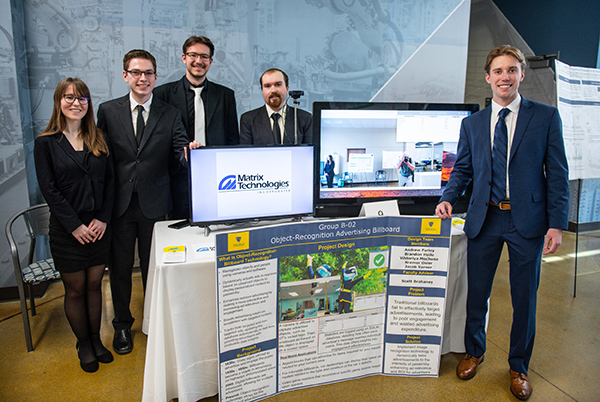 a group of students standing at their presentation table for the senior design project