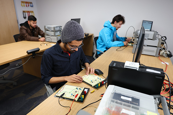 engineering students working on computers and electronics in a classroom
