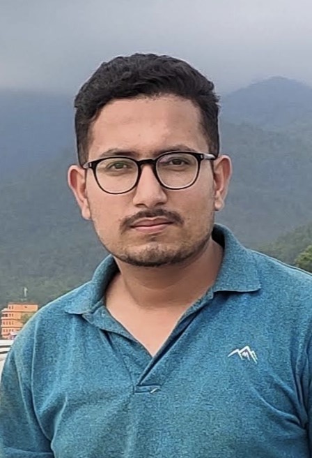 Suraj posing in front of a range of mountains.