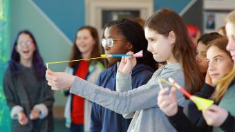 Middle school girls making projectiles with pencils and rubber bands