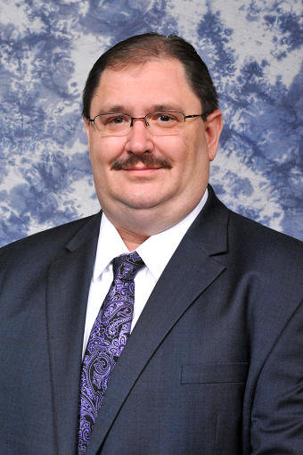 Dark haired smiling man with mustache in blue suit