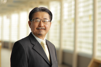 Smiling dark haired man with mustache and glasses in suit and tie