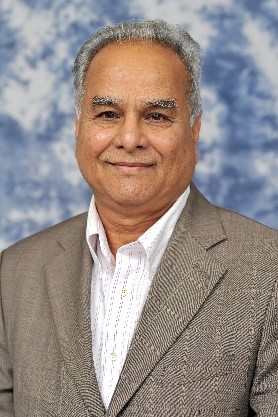 smiling gray haired man in tan suit with white shirt