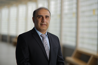 smiling man in dark suit. glass block windows behind him