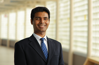 smiling dark haired man in blue suit and tie