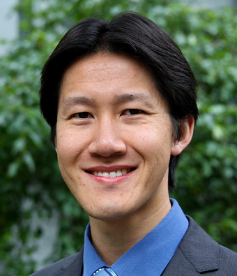 smiling dark haired man in suit standing outside