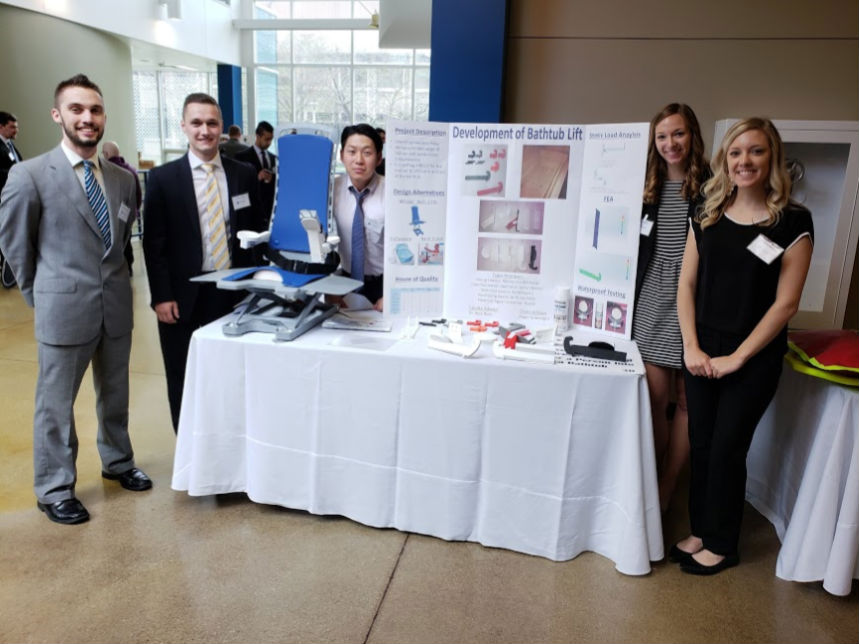 design team standing with bathtub lift on display