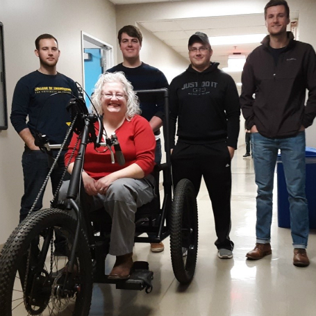 Team members standing with client on adapted tricycle