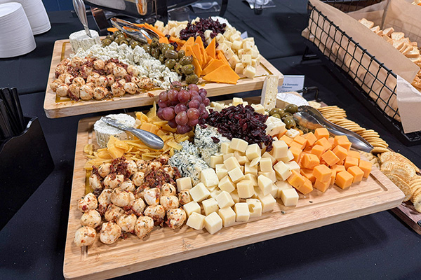 charcuterie board spread with olives, peppers, meats, grapes, cheese, crackers, and plates