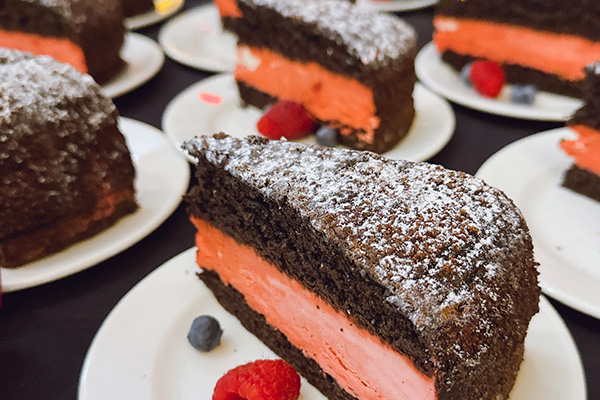 dessert plates of chocolate cake with red filling covered in powdered sugar with a fruit garnish
