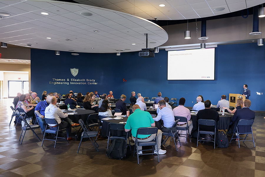 People attend a presentation in the Thomas & Elizabeth Brady Engineering Innovation Center, with a speaker, projection screen, and seated audience.