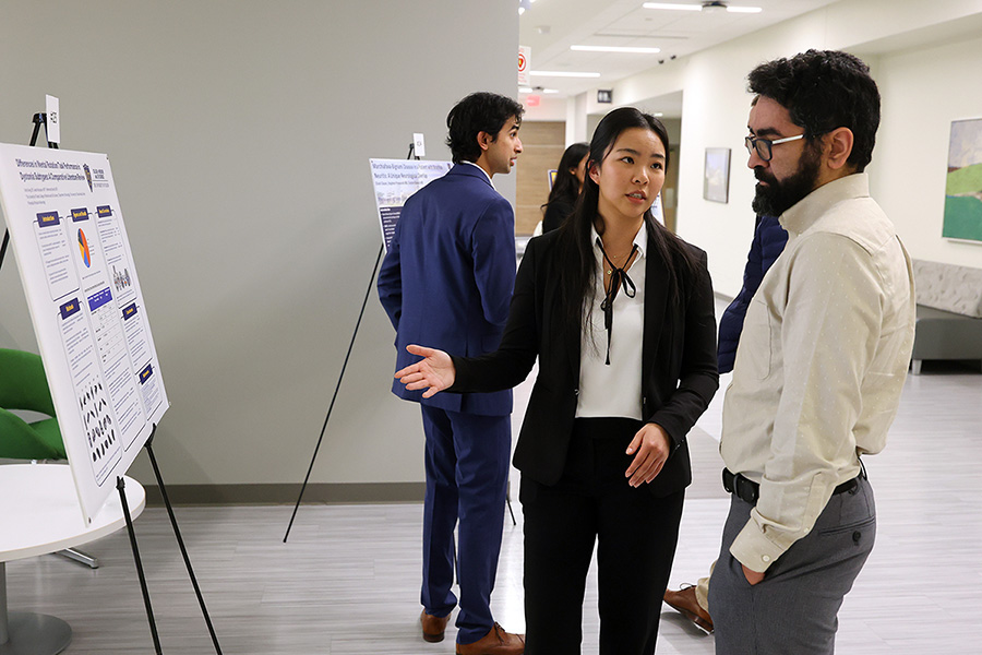 people discussing information on a poster in a hallway