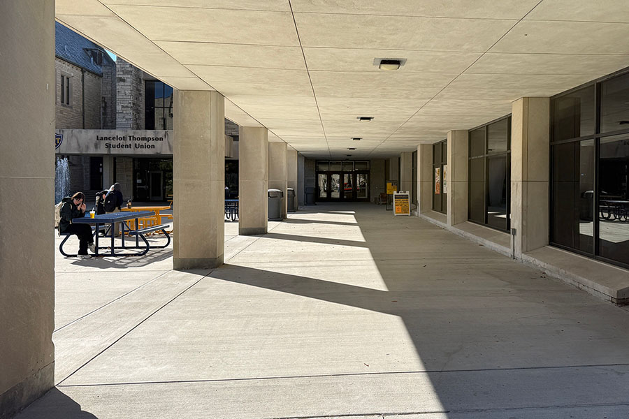 student union overhang walkway with concrete pillars and outdoor picnic tables