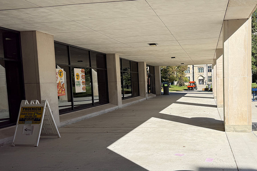 student union overhang walkway with concrete pillars and outdoor picnic tables