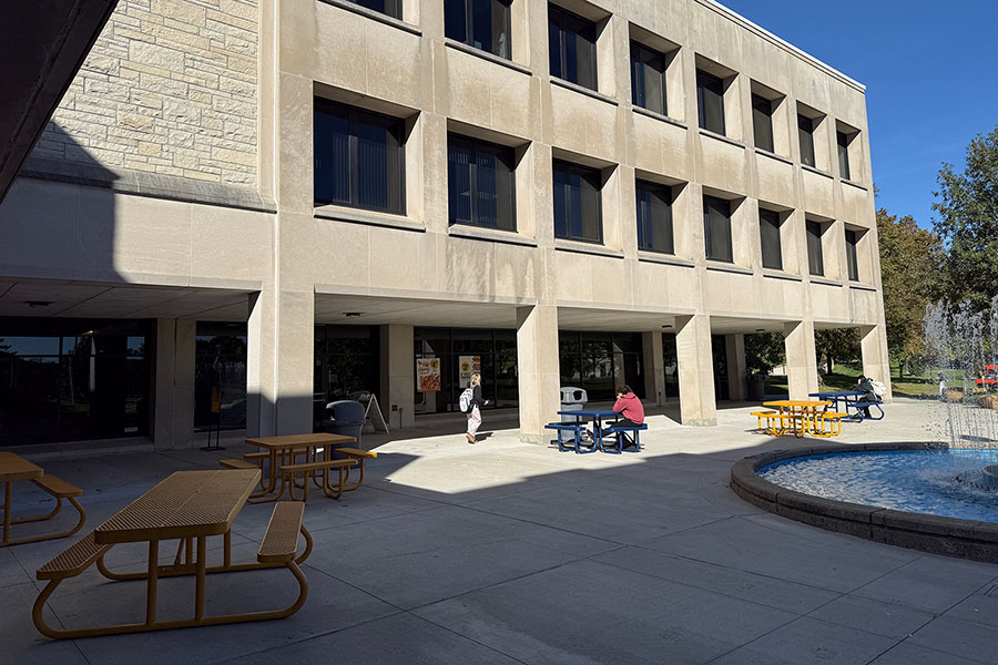 student union overhang walkway with concrete pillars and outdoor picnic tables