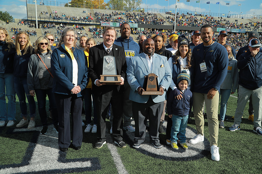 UToledo representatives holding the Cartwright Award on a football field