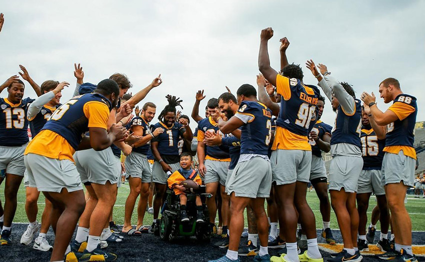 UToledo football team celebrating a child participating in victory day