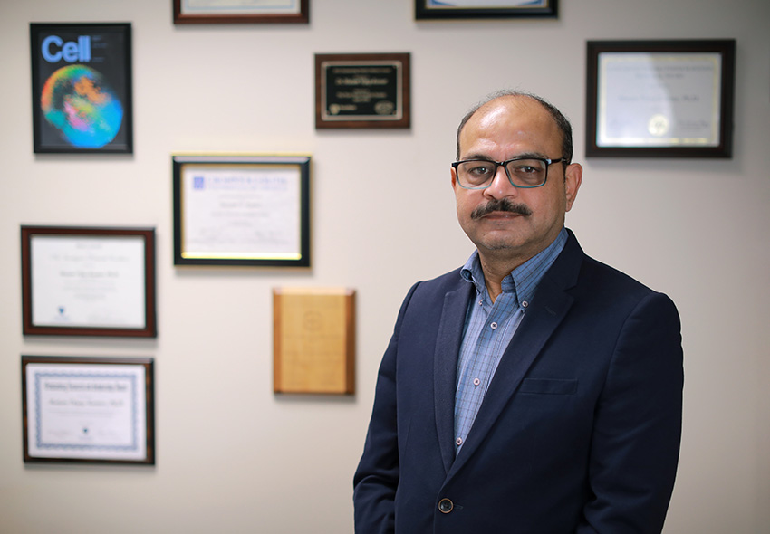 Matam Vijay-Kumar, Ph.D., standing in a room with framed documents on the wall