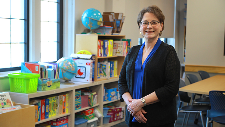 Charlene Czerniak, Ph.D., standing in a classroom with shelves with colorful contents