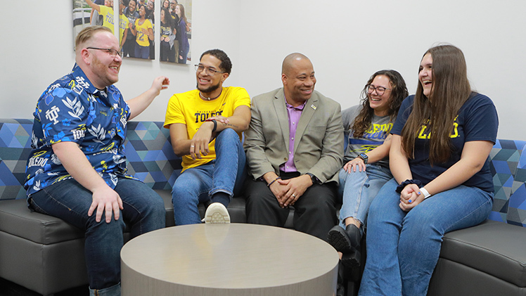 Sammy Spann, Ph.D., and some other adults sitting on a couch smiling and chatting
