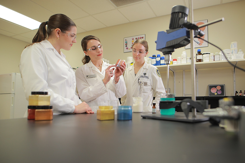 Dr. Gabriella Baki showing lab materials to some students 