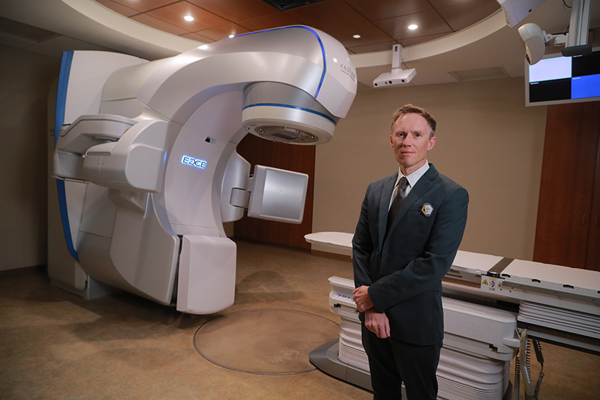 Dr. David Pearson standing in front of a large medical radiation machine