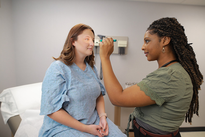 A medical worker shining a light in a patient's eye for examination