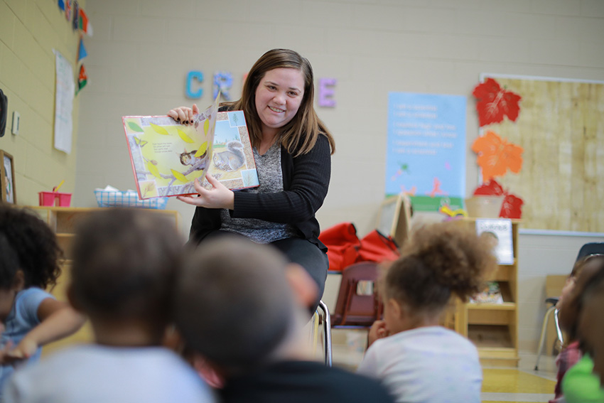 A teacher reading a book to a group of young children.