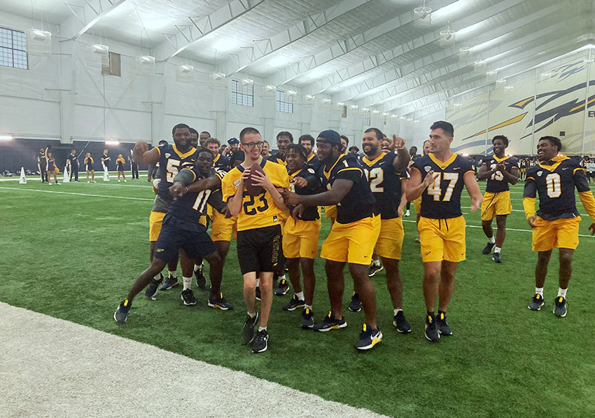 Rocket football players celebrate a touchdown with a young participant in their annual Victory Day.