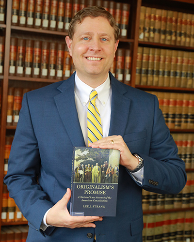 Lee Strang, J.D., holding a copy of his newly released book, Originalism's Promise: A Natural Law Account of the American Constitution