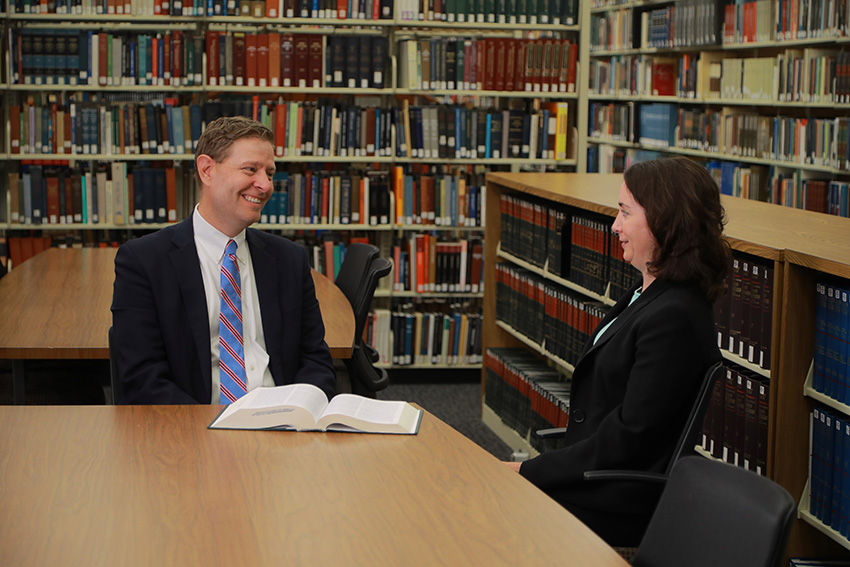 Two well-dressed adults conversing in UToledo's law library.