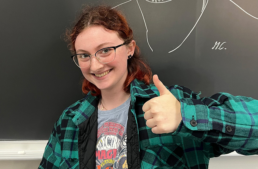 Milo Eckhardt giving a thumbs up in front of a blackboard