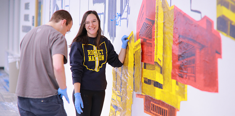 two students putting up an art display