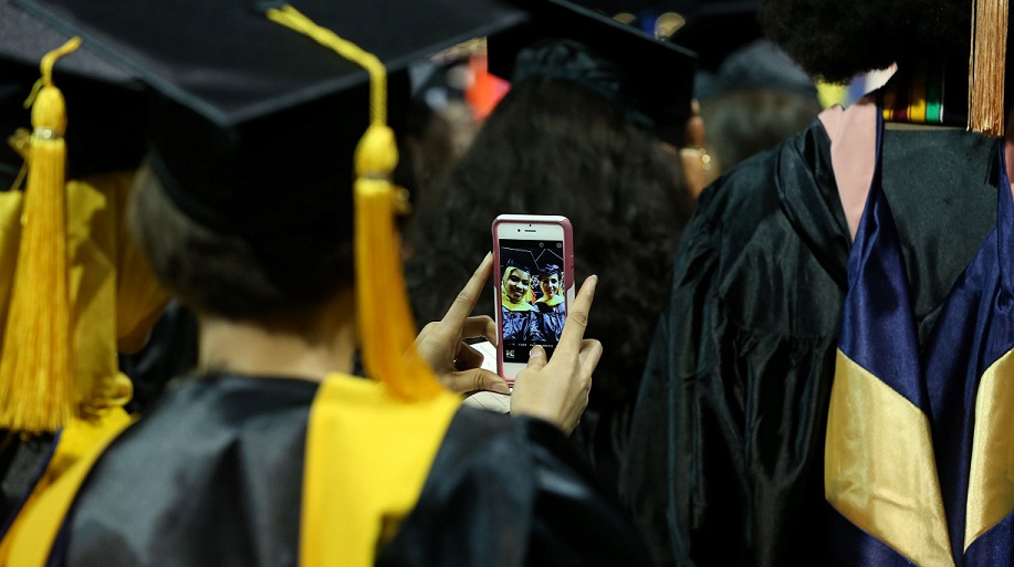 Two graduate students take a selfie at commencement