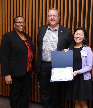 Photograph of Dean Bryant-Friedrich, Dr. Randy Worth, and Claire Meikel, the winner of the 3MT competition, receiving her certificate of recognition