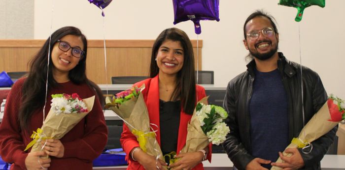 Three Minute Thesis 2023 winners standing side by side and holding flowers