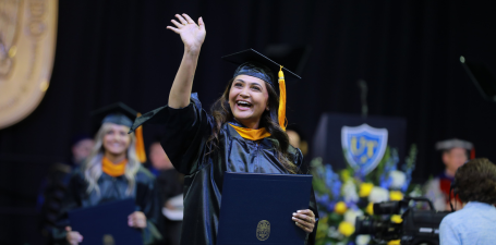 Graduate waving at Graduate Commencement in MSN regalia