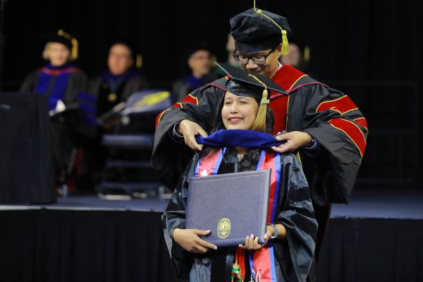 Women in regalia and stole being hooded at commencement