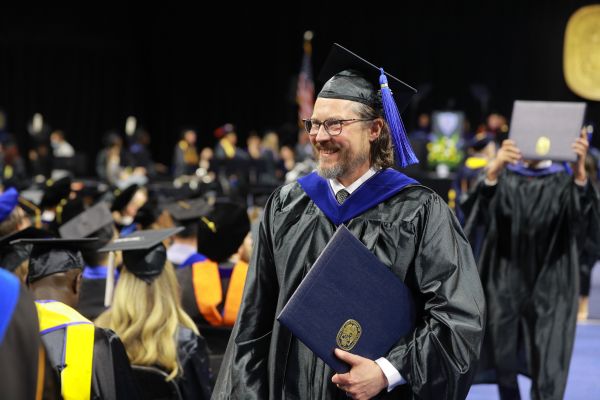 Man in master's regalia including blue hood and tassel