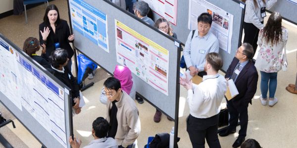 Students presenter in front of posters to peers and judges