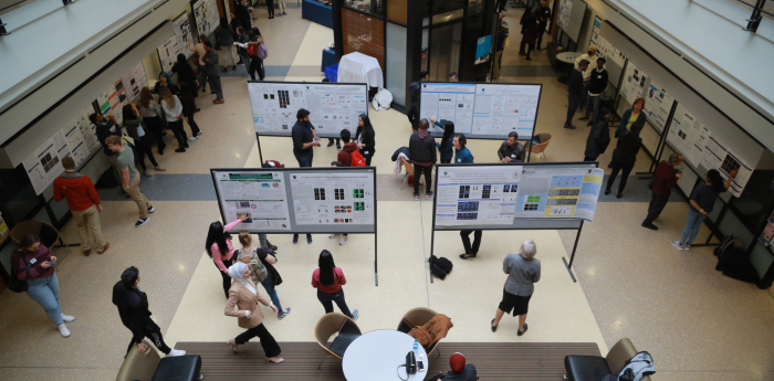 Students, staff, and faculty gathering in Field House lobby with research posters.