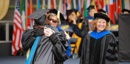 Doctor of Occupational Therapy candidate hugging hooder at commencement 