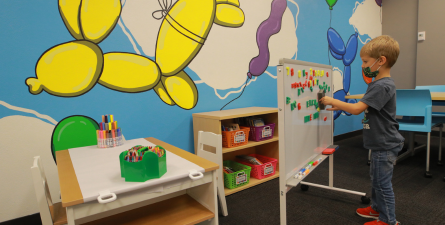 Child playing with whiteboard in Carlson Library student parent resource room