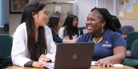 College of Pharmacy students smiling and using laptop