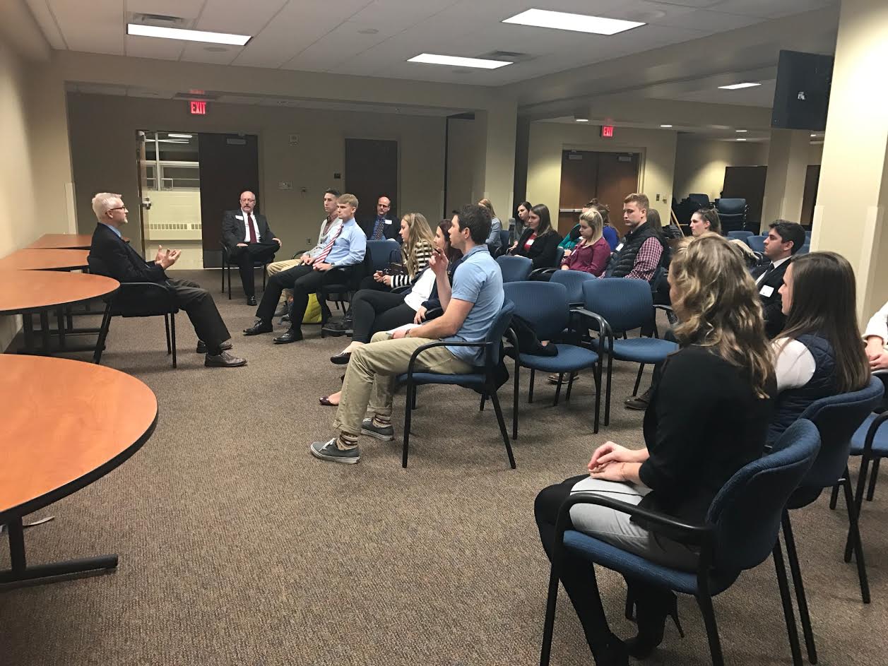 a group of students sitting in front of a male guest speaker